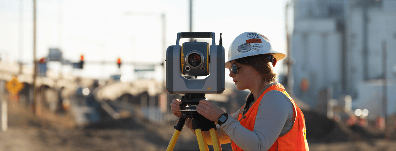 Surveyor using land surveying equipment on a construction site.